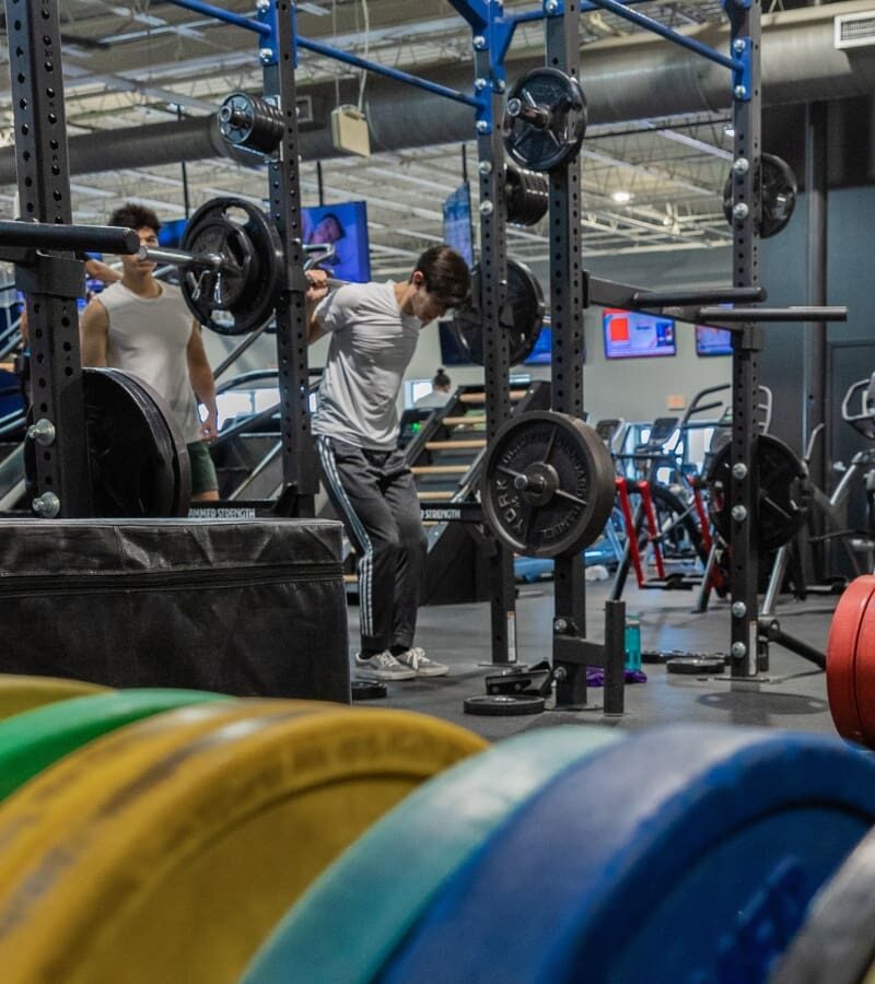 gym members do squats in an open and spacious weight training area at a hershey pa fitness gym