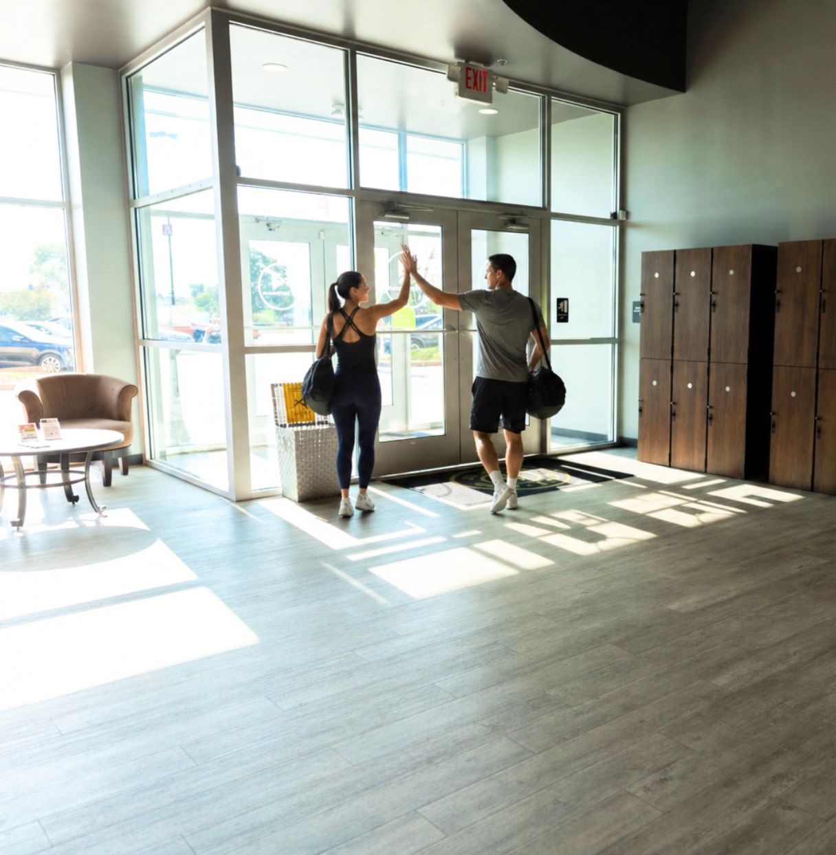Two members high-fiving near the exit at PA Fitness Galleria in York, PA.
